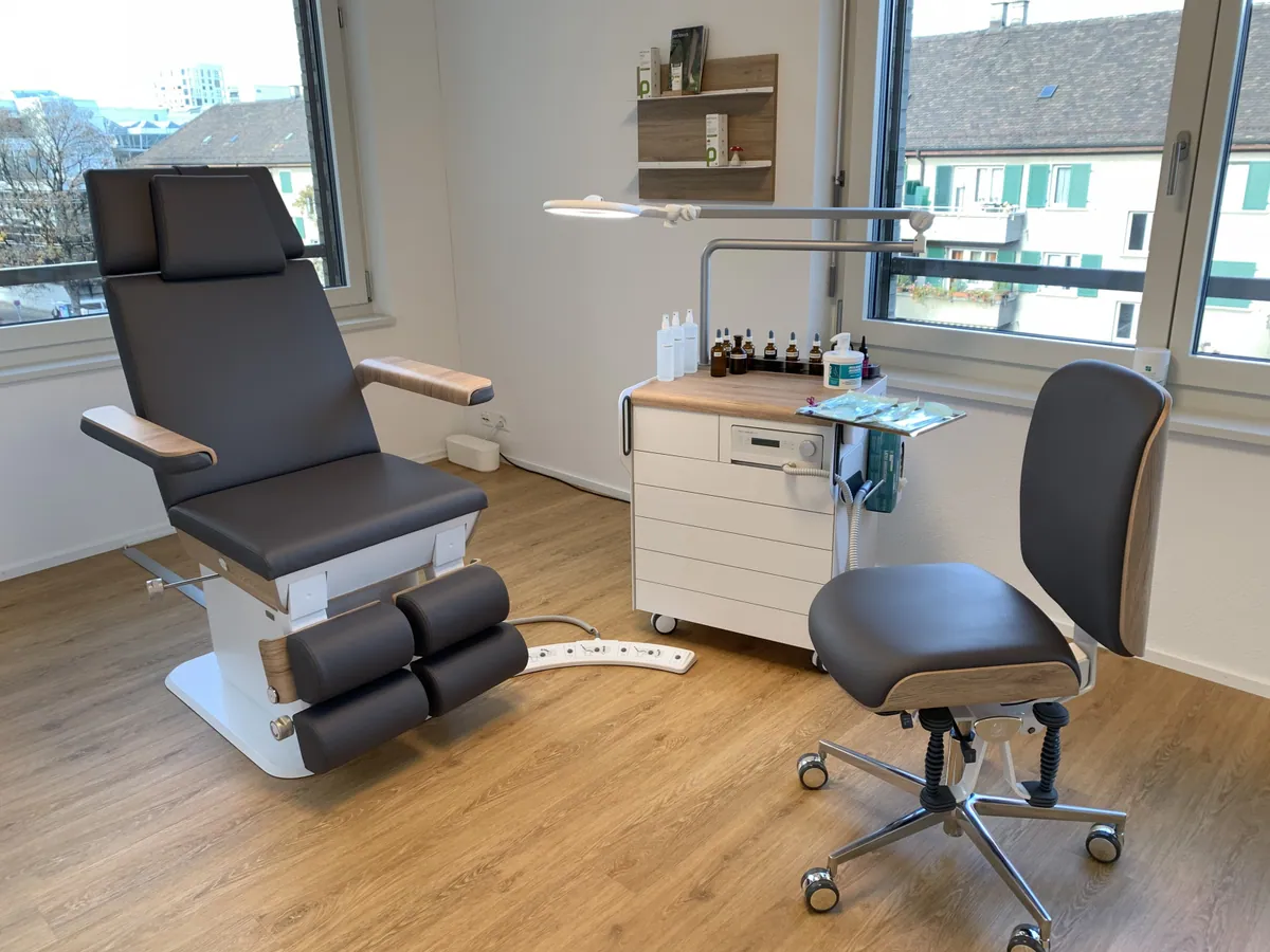 Heller Behandlungsraum mit Podologiestuhl und Arbeitsinstrumenten am Fenster