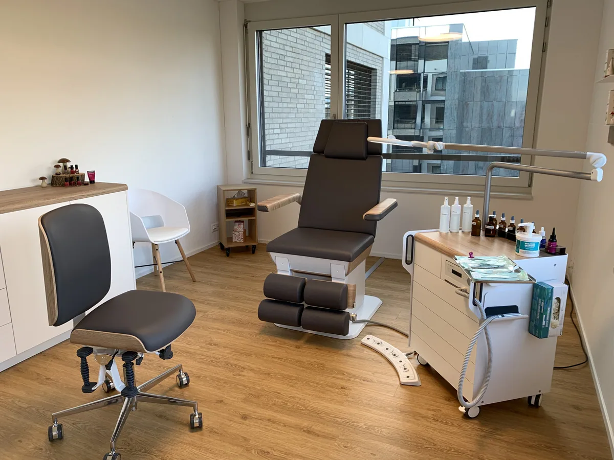 Behandlungsstuhl am Fenster mit Arbeitswagen und Sitz für die Podologin